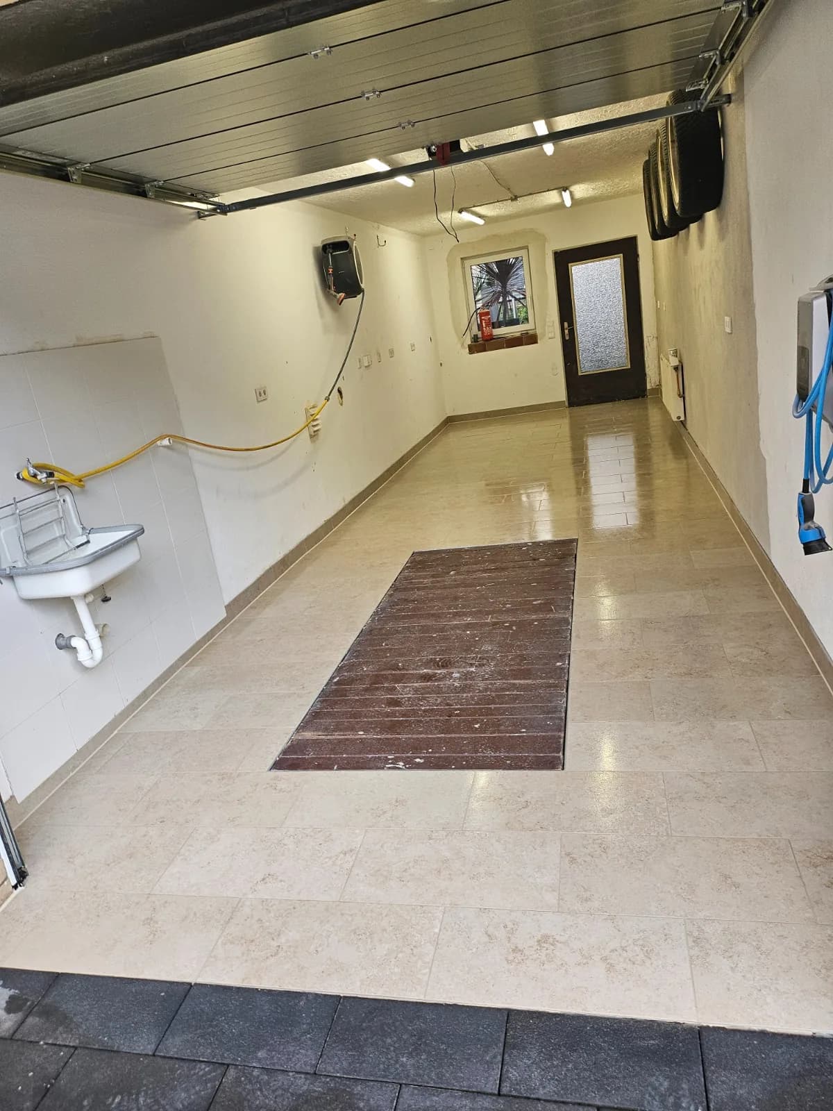 Garage mit hellem Fliesenboden und frisch gestrichenen Wänden