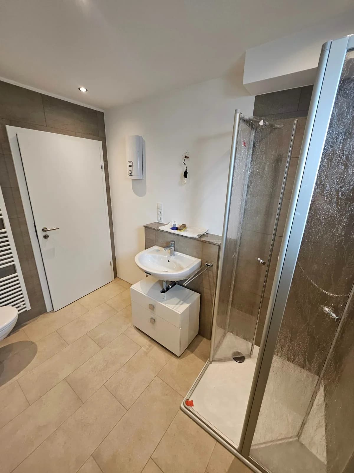 Blick auf Dusche und Waschtisch im gefliesten Badezimmer