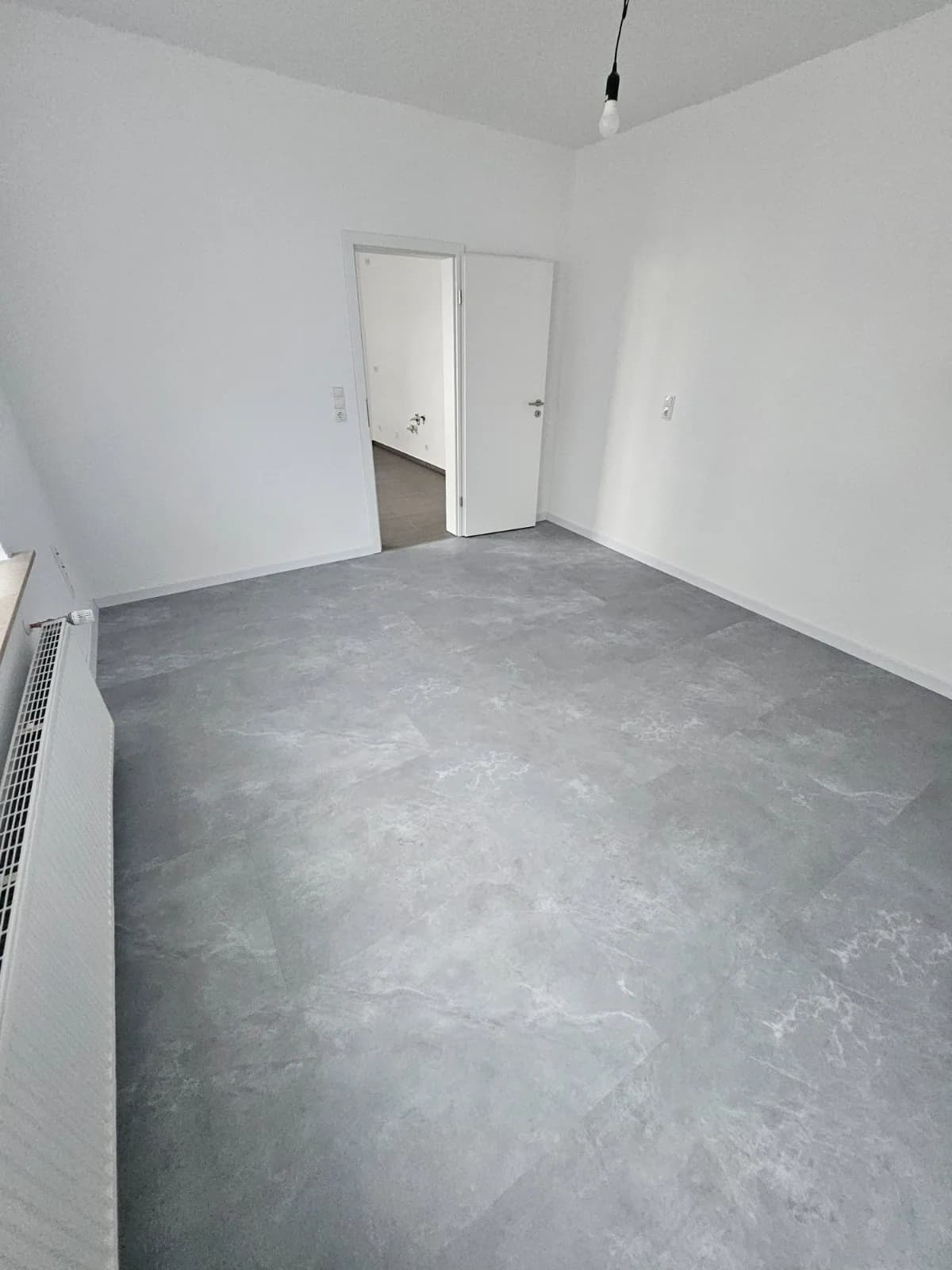 Zimmer mit grauem Bodenbelag, weißen Wänden und eingebauten weißen Zimmertüren