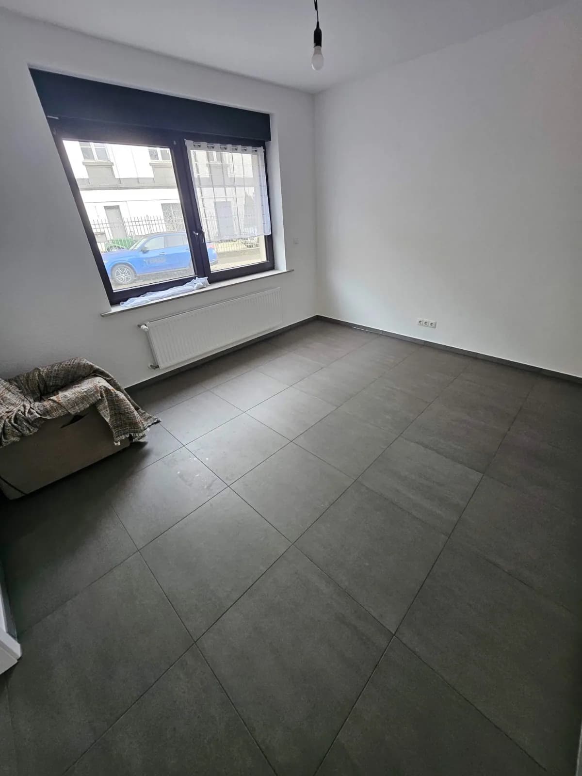 Dunkler Boden in Fliesenoptik im Wohnraum mit großem Fenster
