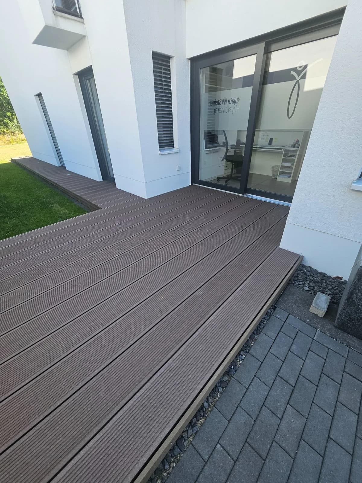 Neue WPC-Terrasse entlang der Hausfassade mit angrenzendem Pflasterweg