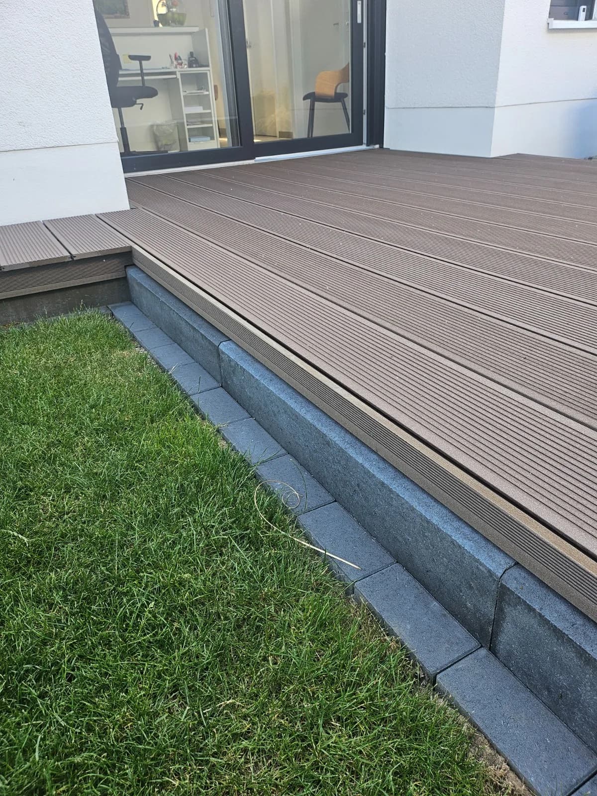 WPC-Terrasse mit Stufe und Betonkante zum Rasen