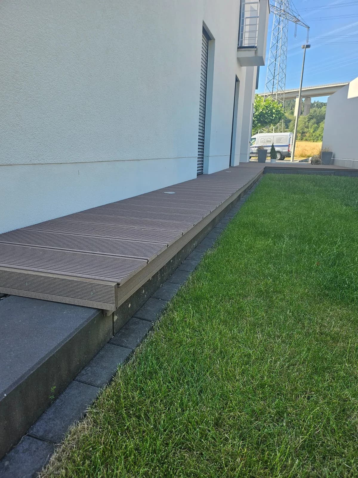 Längsseite der WPC-Terrasse zwischen Hauswand und Rasen